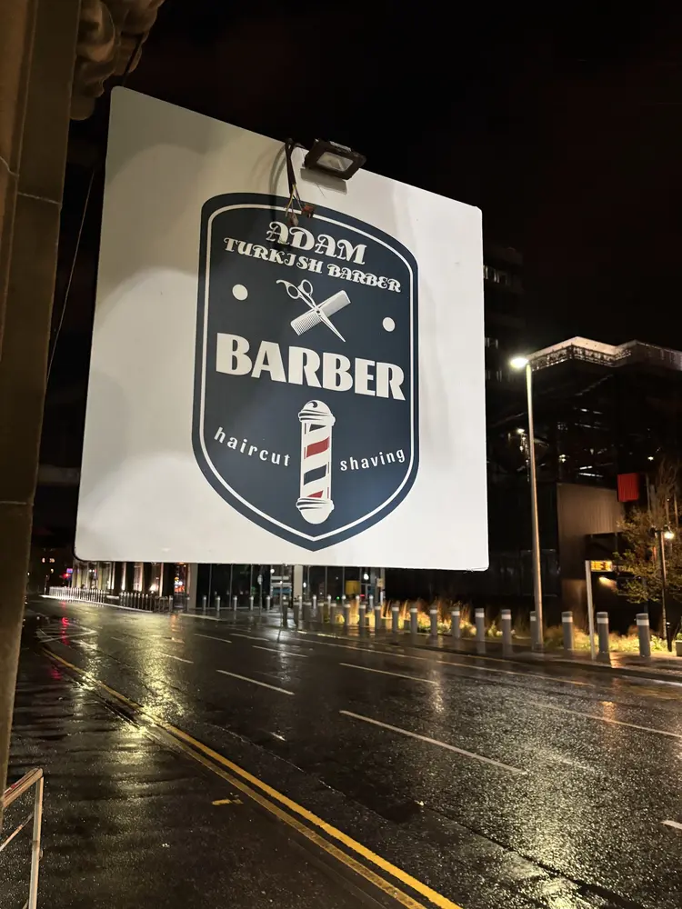 Adam Turkish Barber's illuminated shield sign after dark